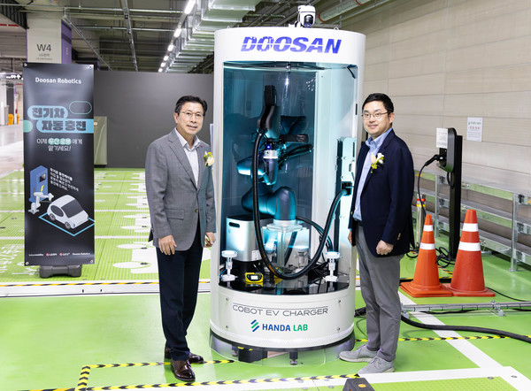  두산로보틱스 류정훈 대표(오른쪽)와 LG전자 장익환 BS사업본부장이 협동로봇을 활용한 전기차 자동 충전 솔루션 옆에서 기념사진을 촬영하고 있다.​​
