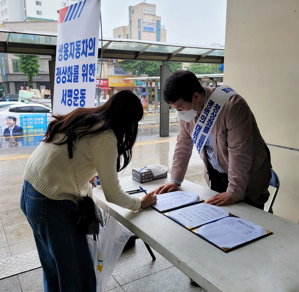 쌍용차 살리기 서명을 받는 평택대 총동문회장 겸 김수우 브레인시티 대표(오른쪽)