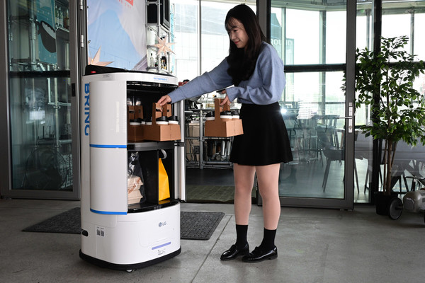  LG 클로이 서브봇(양문형)은 4칸의 서랍에 보통 크기(약 350㎖)의 커피를 최대 32잔까지 탑재할 수 있다. 공간 내부에는 위생을 고려해 항균 처리된 소재 및 탈취용 환기팬이 적용됐다. (사진= LG전자 모델이 클로이 로봇의 서랍에 배송 물품을 적재하는 모습.)